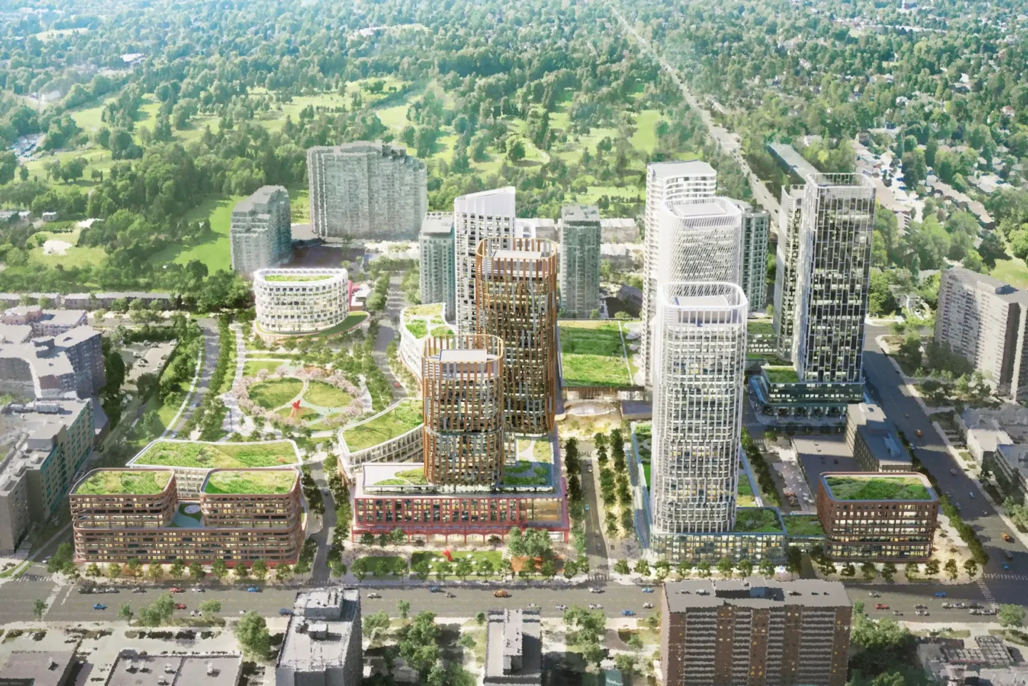 A detailed aerial rendering of a proposed urban redevelopment project featuring a cluster of mid- and high-rise buildings with modern architectural designs. The buildings are surrounded by green rooftops, landscaped plazas, walking paths, and open park areas. A circular building and multiple towers of varying heights form the focal point of the development. The community is embedded in a suburban area with existing apartment buildings, low-rise structures, and a vast green space stretching out toward the horizon. Roads and tree-lined streets intersect the scene, blending the new development into the surrounding neighborhood.