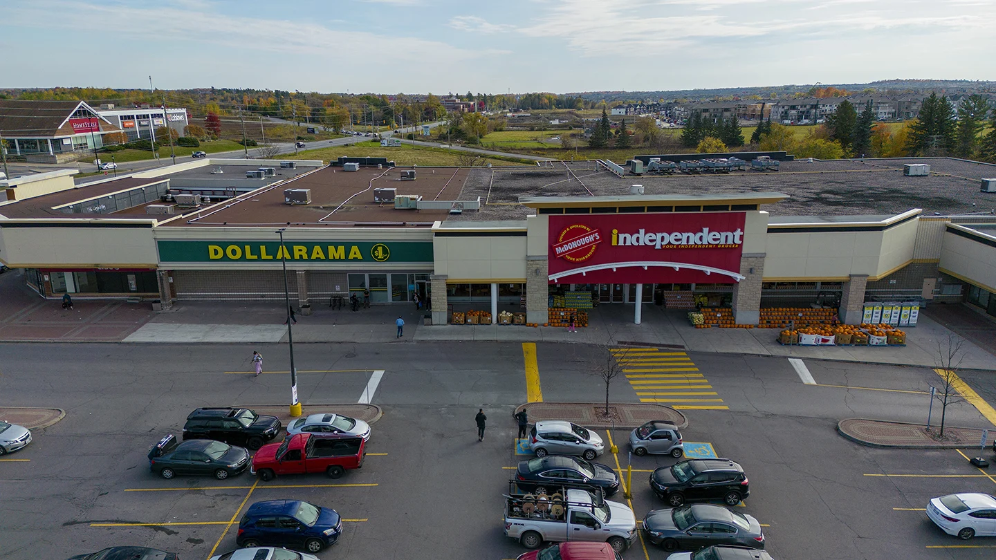 Elevated view of a plaza in Barrhaven Town Centre featuring a Dollarama store with a green and yellow sign on the left, and McDonough