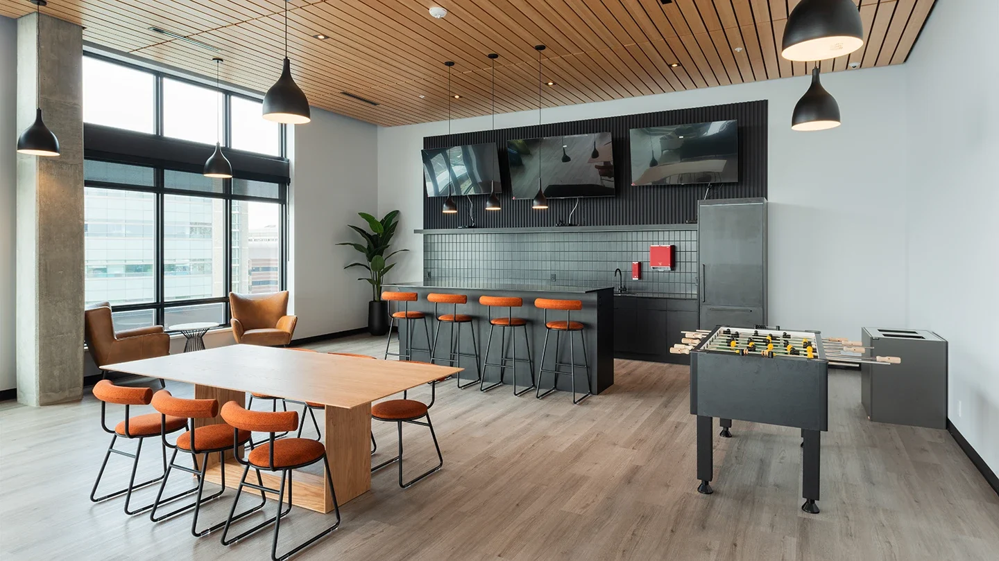 Spacious lounge with contemporary furniture, large windows for natural light, and stylish pendant lighting arranged over a central seating area.