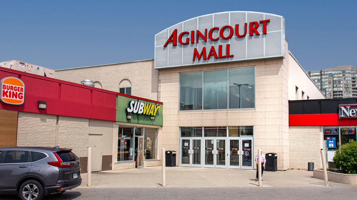 Exterior view of Agincourt Mall showing large red signage above a glass entryway, flanked by Burger King and Subway storefronts.