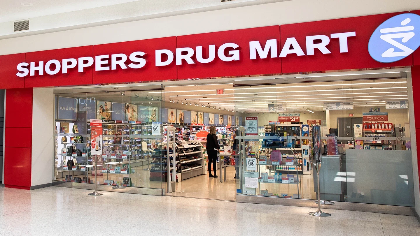 Front entrance of Shoppers Drug Mart inside Lynden Park Mall, showing clear signage, automatic doors, and promotional displays in the windows.