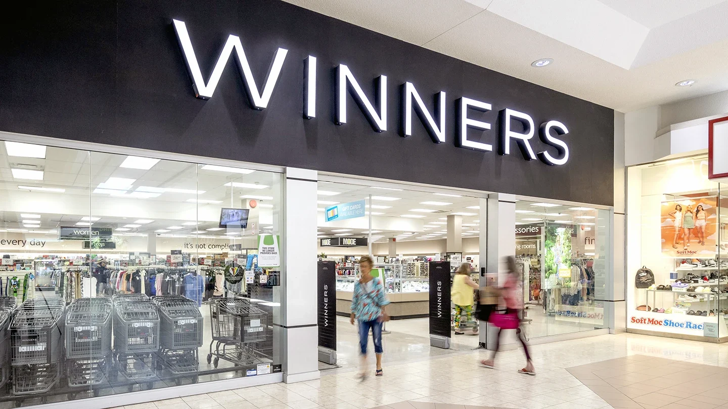Storefront of Winners inside Lynden Park Mall, featuring bright signage above large glass windows and visible racks of clothing and shopping carts inside.