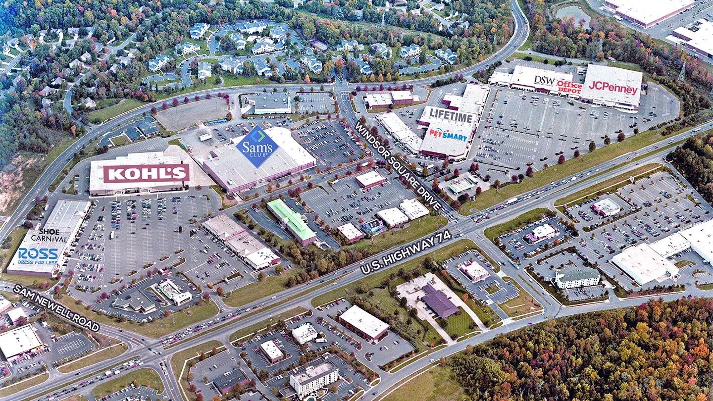 Aerial view of Windsor Square shopping center and surrounding retail area in a suburban setting. Major retailers are labeled, including Kohl’s, Sam’s Club, Shoe Carnival, Ross, PetSmart, Lifetime Fitness, DSW, Office Depot, and JCPenney. The complex is bordered by Windsor Square Drive, Sam Newell Road, and U.S. Highway 74, with parking lots and smaller buildings spread throughout. Trees and residential neighborhoods are visible in the background.
